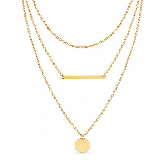 Triple layer gold necklace with short cable chain, bar pendant, and coin pendant on white background